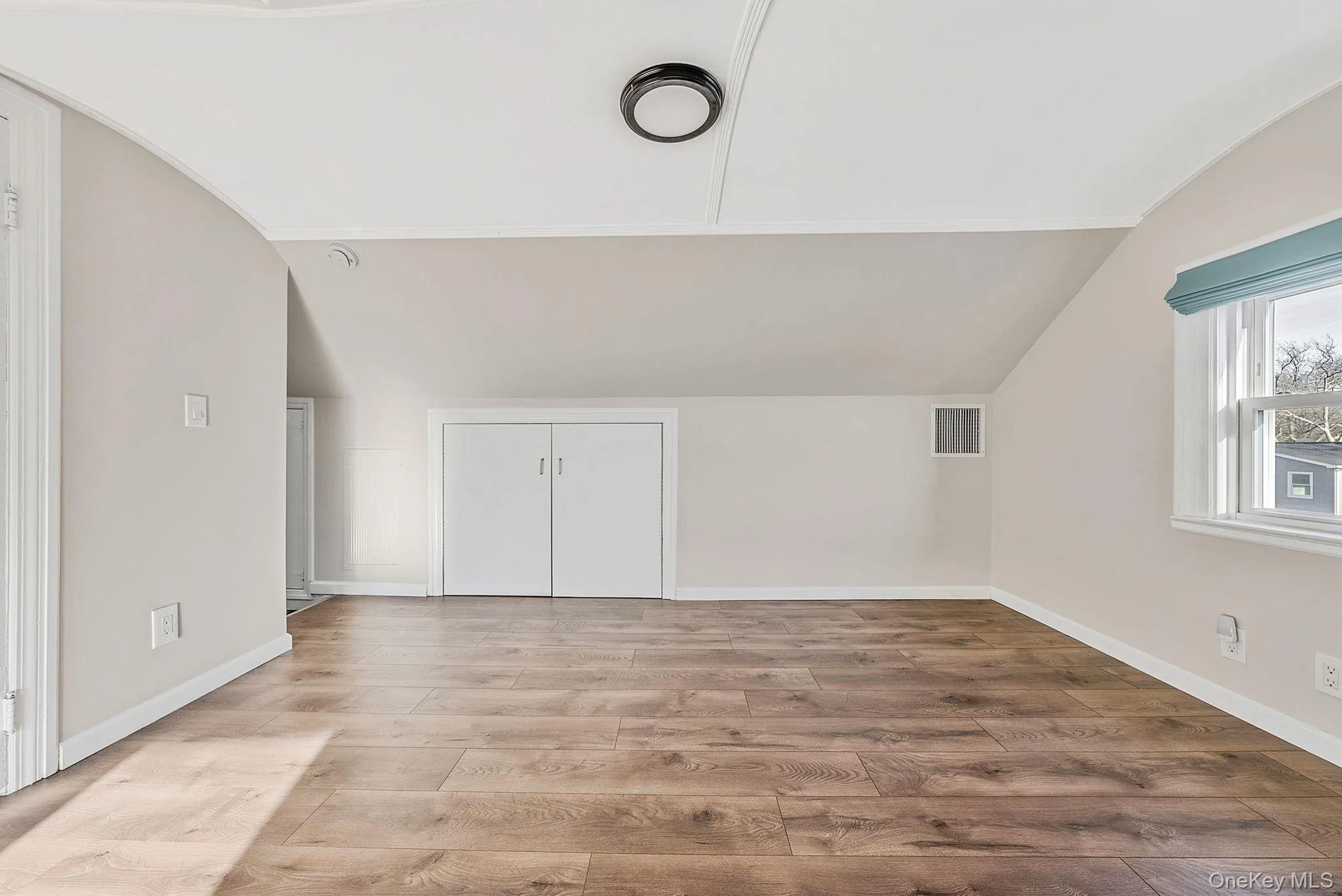 Additional living space featuring vaulted ceiling, wood finished floors, and arched walkways Additional living space featuring vaulted ceiling, wood finished floors, and arched walkways