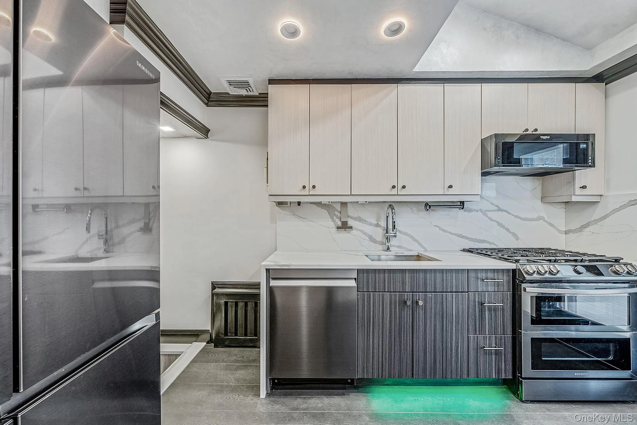 Kitchen featuring appliances with stainless steel finishes, backsplash, white cabinetry, light stone counters, and gray cabinetry Kitchen featuring appliances with stainless steel finishes, backsplash, white cabinetry, light stone counters, and gray cabinetry