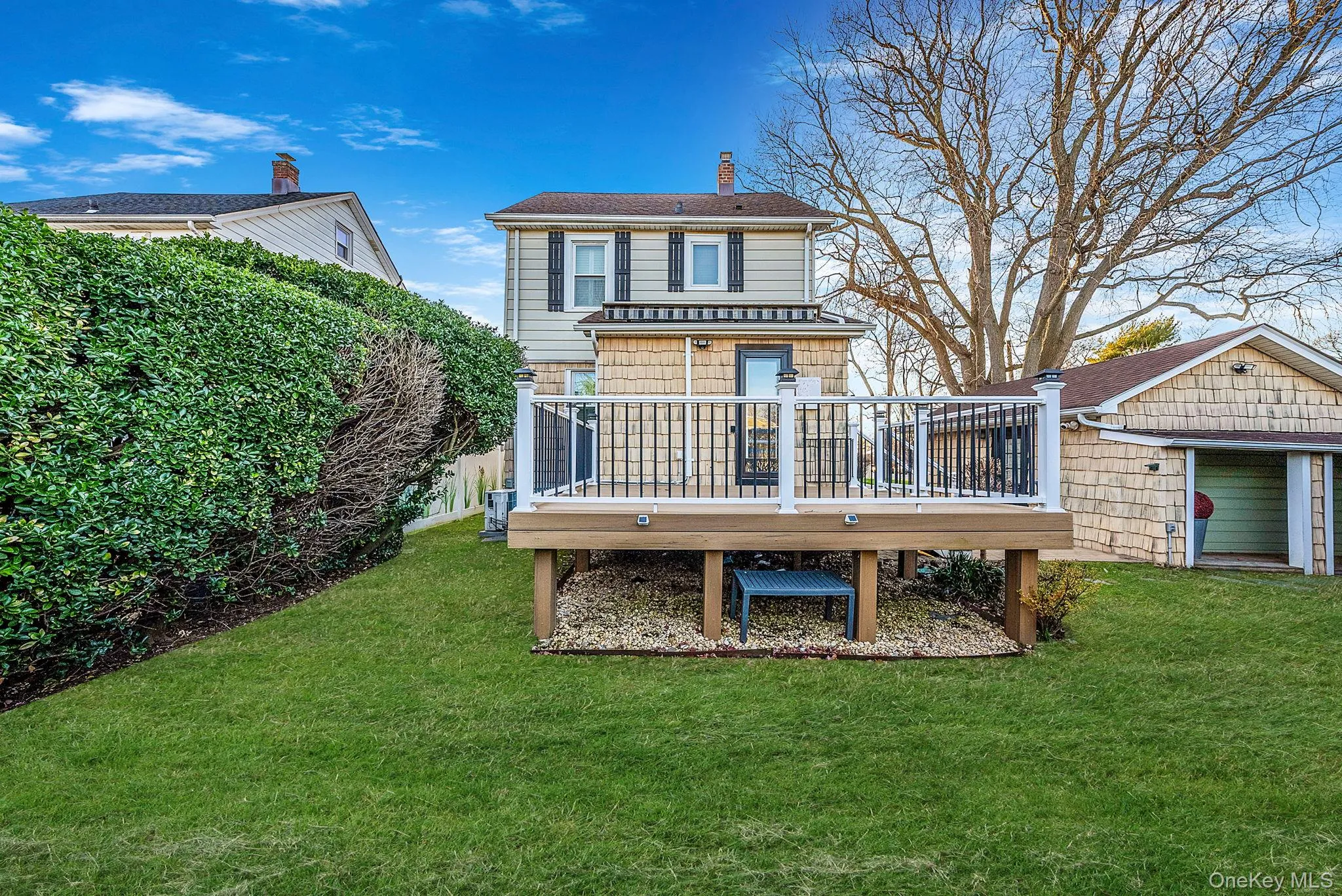 Back of property featuring a wooden deck, a lawn, and a chimney Back of property featuring a wooden deck, a lawn, and a chimney