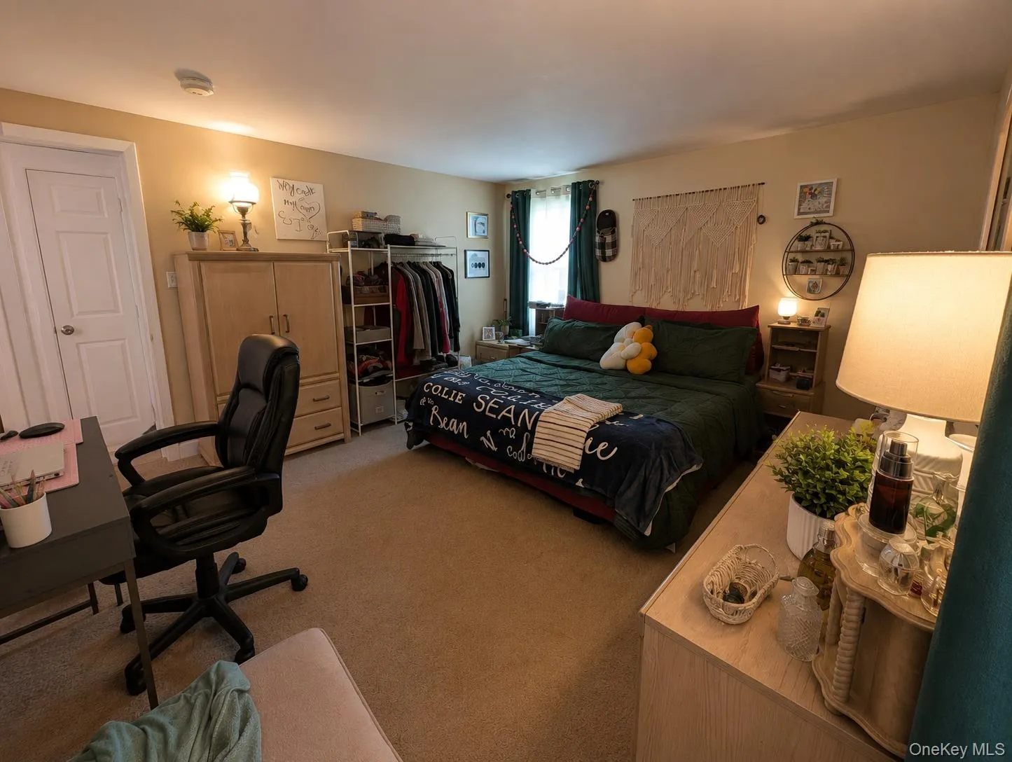 Carpeted bedroom featuring neutral wall tones, a solid core door, and a built-in window with drapes Carpeted bedroom featuring neutral wall tones, a solid core door, and a built-in window with drapes