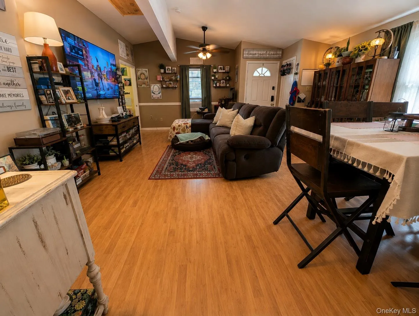 Open concept living space featuring wood-finish flooring, vaulted ceilings with an exposed beam, and a ceiling fan Open concept living space featuring wood-finish flooring, vaulted ceilings with an exposed beam, and a ceiling fan