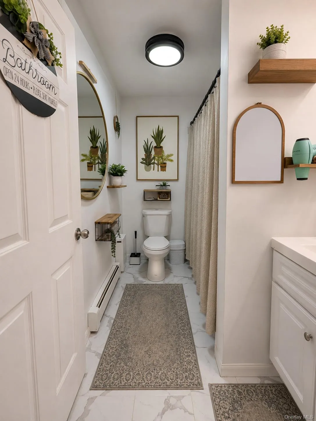 Bathroom featuring white marble-look tile flooring, a white vanity with panel detailing, and a flush-mount ceiling light fixture Bathroom featuring white marble-look tile flooring, a white vanity with panel detailing, and a flush-mount ceiling light fixture