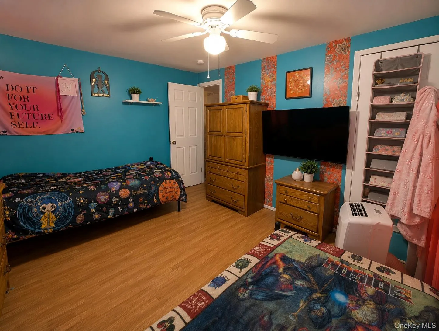 Interior room featuring wood-finish flooring, a white ceiling fan, and a wall-mounted television Interior room featuring wood-finish flooring, a white ceiling fan, and a wall-mounted television