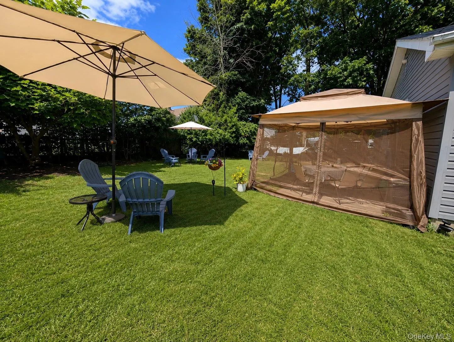 Expansive lawn area featuring a screened gazebo and a large patio umbrella Expansive lawn area featuring a screened gazebo and a large patio umbrella