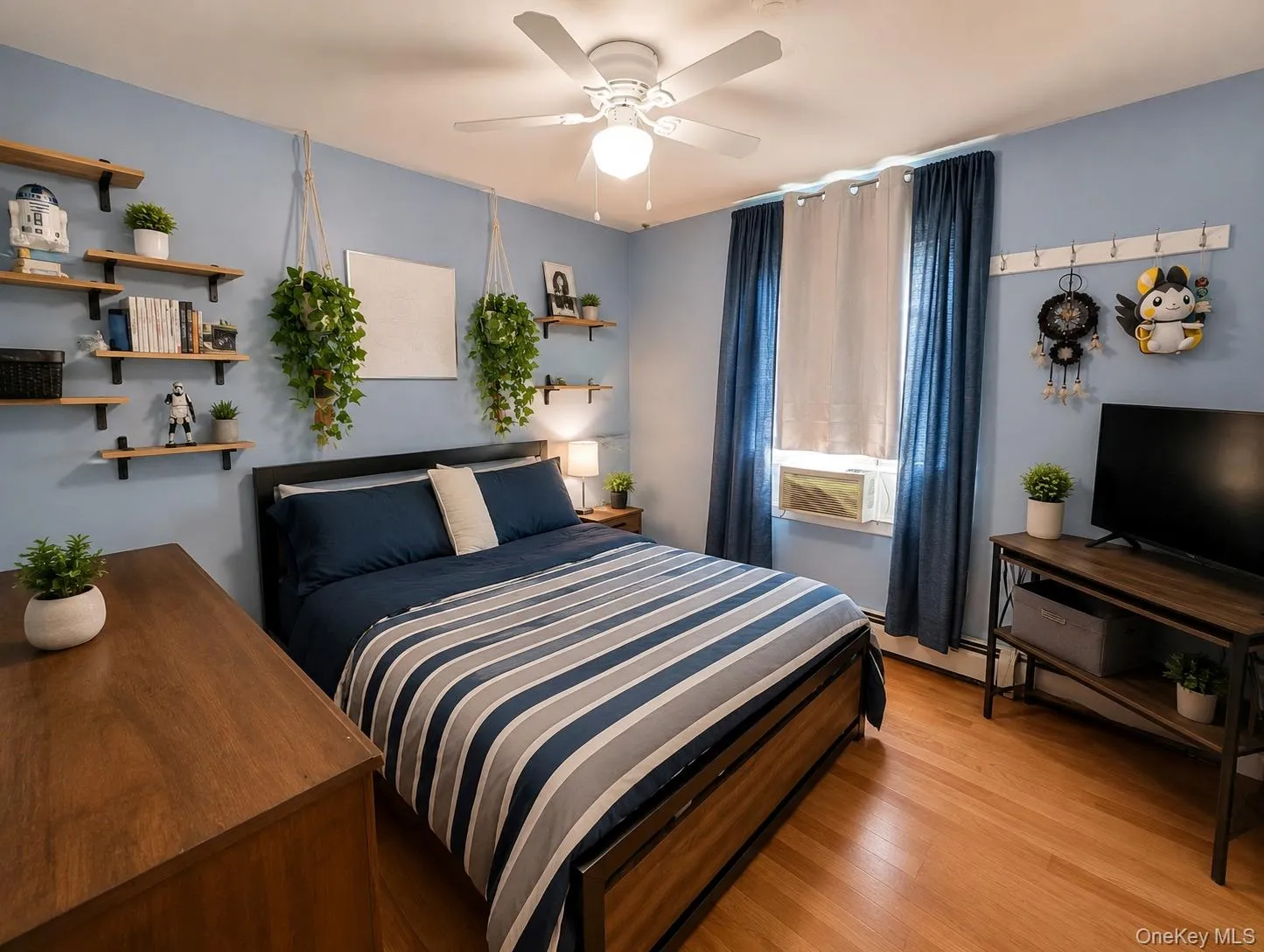 2nd bedroom featuring light blue walls, wood-finish flooring, a ceiling fan with integrated lighting, and a window with dual curtain panels 2nd bedroom featuring light blue walls, wood-finish flooring, a ceiling fan with integrated lighting, and a window with dual curtain panels