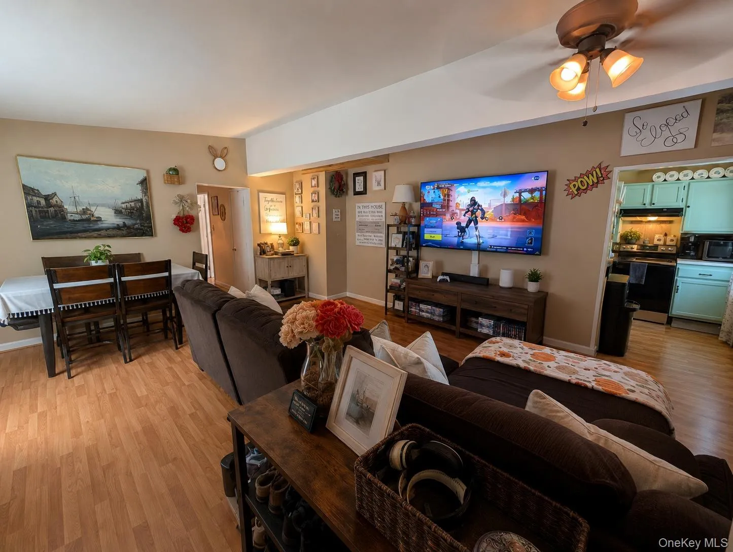 Open-concept living space featuring wood-finish flooring, a contemporary ceiling fan with integrated lighting, and a dining area with a high-top table Open-concept living space featuring wood-finish flooring, a contemporary ceiling fan with integrated lighting, and a dining area with a high-top table