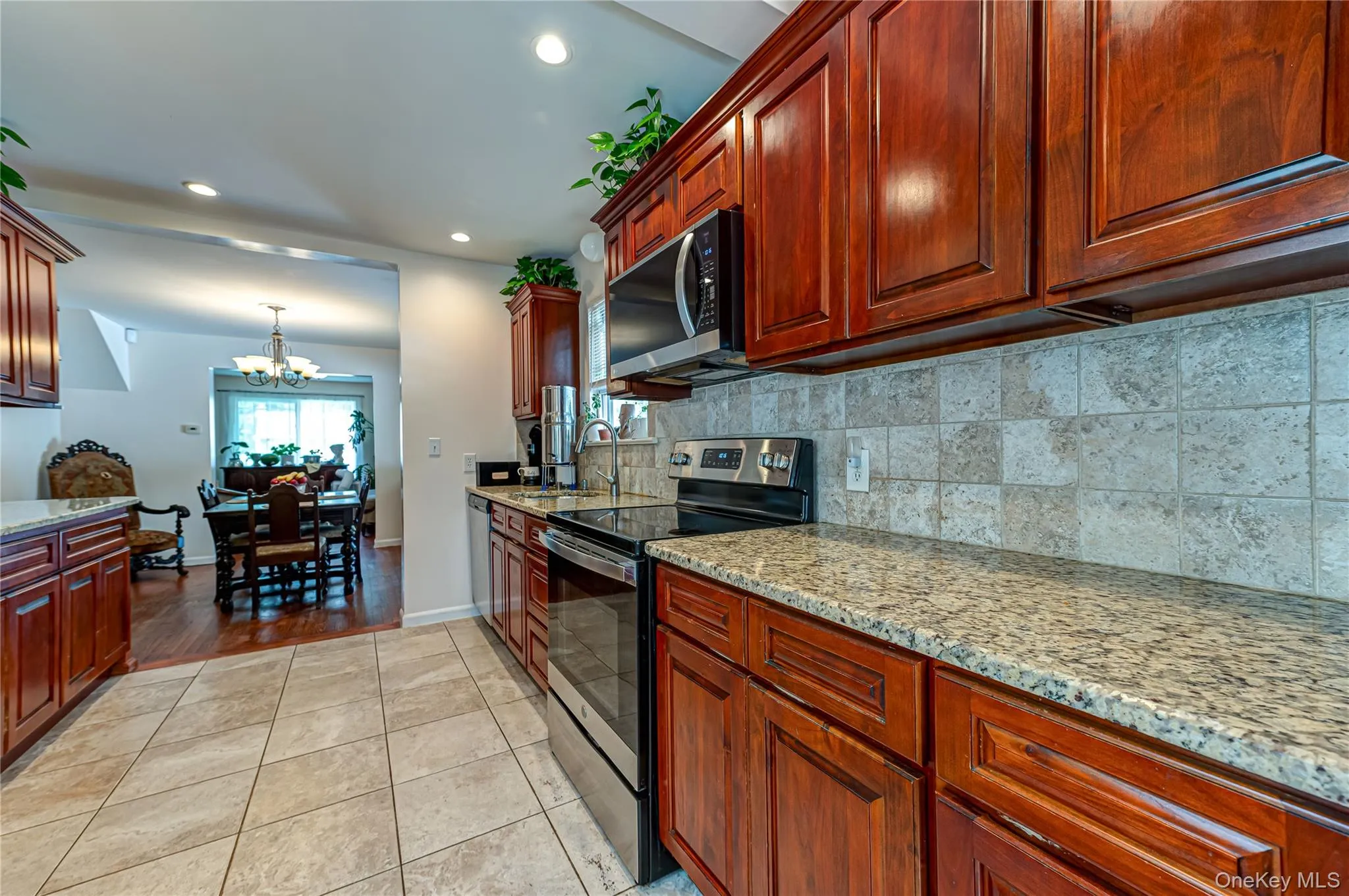 Kitchen featuring wood cabinetry, granite countertops, tile backsplash, and stainless steel appliances Kitchen featuring wood cabinetry, granite countertops, tile backsplash, and stainless steel appliances