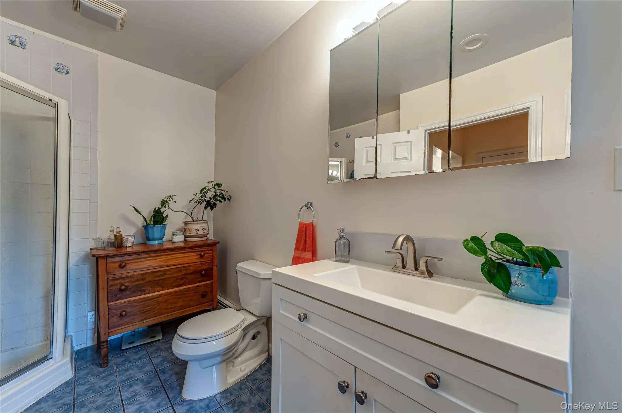 Bathroom featuring a white vanity with an integrated sink, brushed nickel faucet, and a mirrored medicine cabinet Bathroom featuring a white vanity with an integrated sink, brushed nickel faucet, and a mirrored medicine cabinet