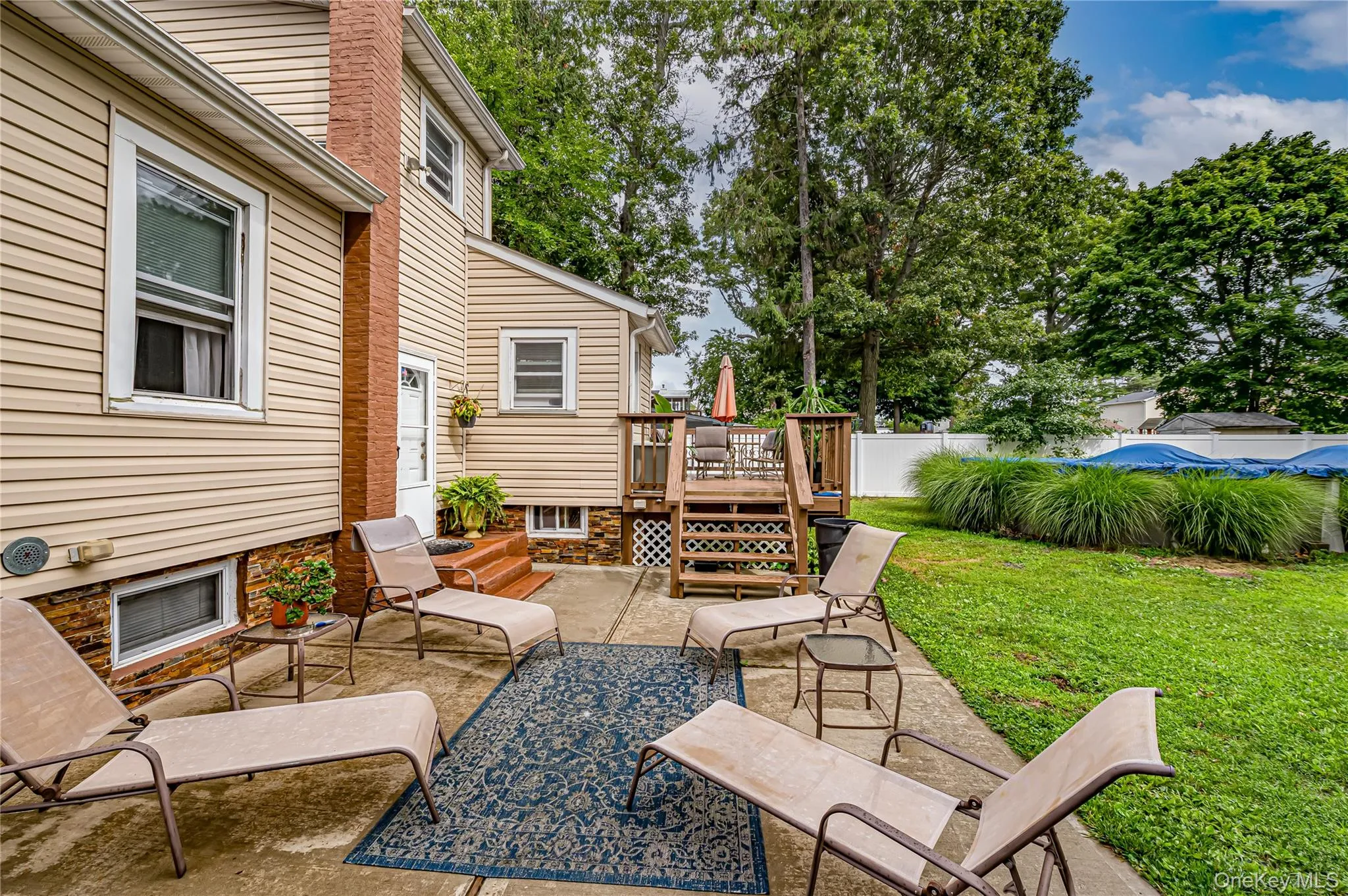Outdoor patio area featuring concrete flooring and a wooden deck with railing Outdoor patio area featuring concrete flooring and a wooden deck with railing