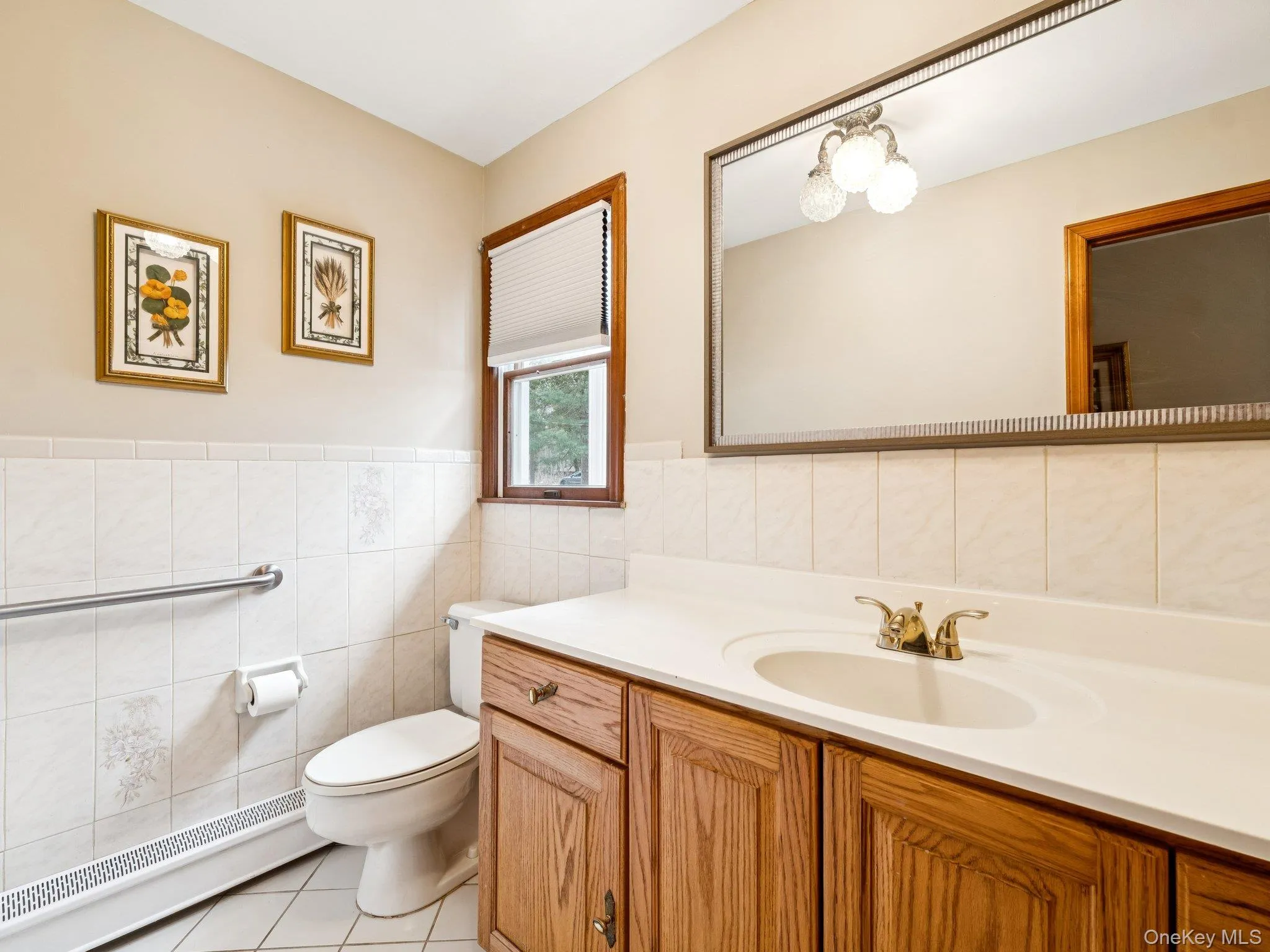 Bathroom featuring baseboard heating, light tile patterned floors, vanity, tile walls, and a wainscoted wall Bathroom featuring baseboard heating, light tile patterned floors, vanity, tile walls, and a wainscoted wall