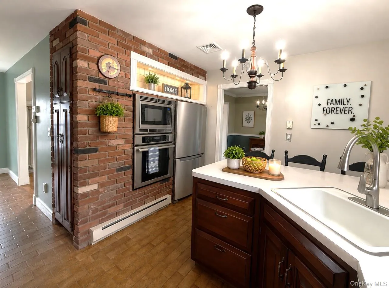 Kitchen featuring a prominent brick-clad wall with built-in stainless steel appliances Kitchen featuring a prominent brick-clad wall with built-in stainless steel appliances
