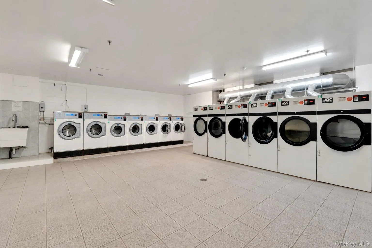Community laundry facility featuring multiple commercial-grade washers and dryers in the basement. Community laundry facility featuring multiple commercial-grade washers and dryers in the basement.