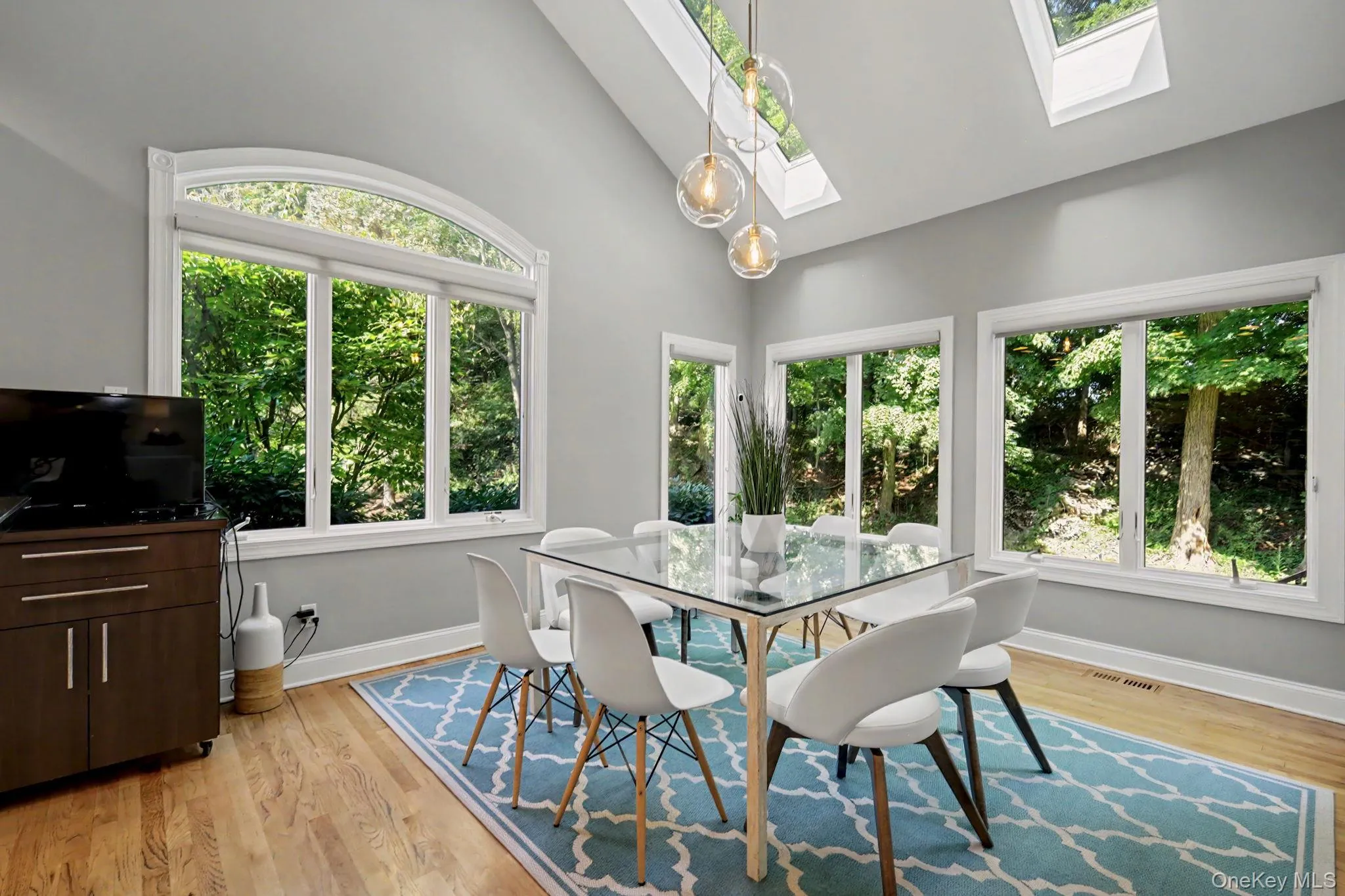 Vaulted ceiling dining area featuring expansive windows and multiple skylights Vaulted ceiling dining area featuring expansive windows and multiple skylights