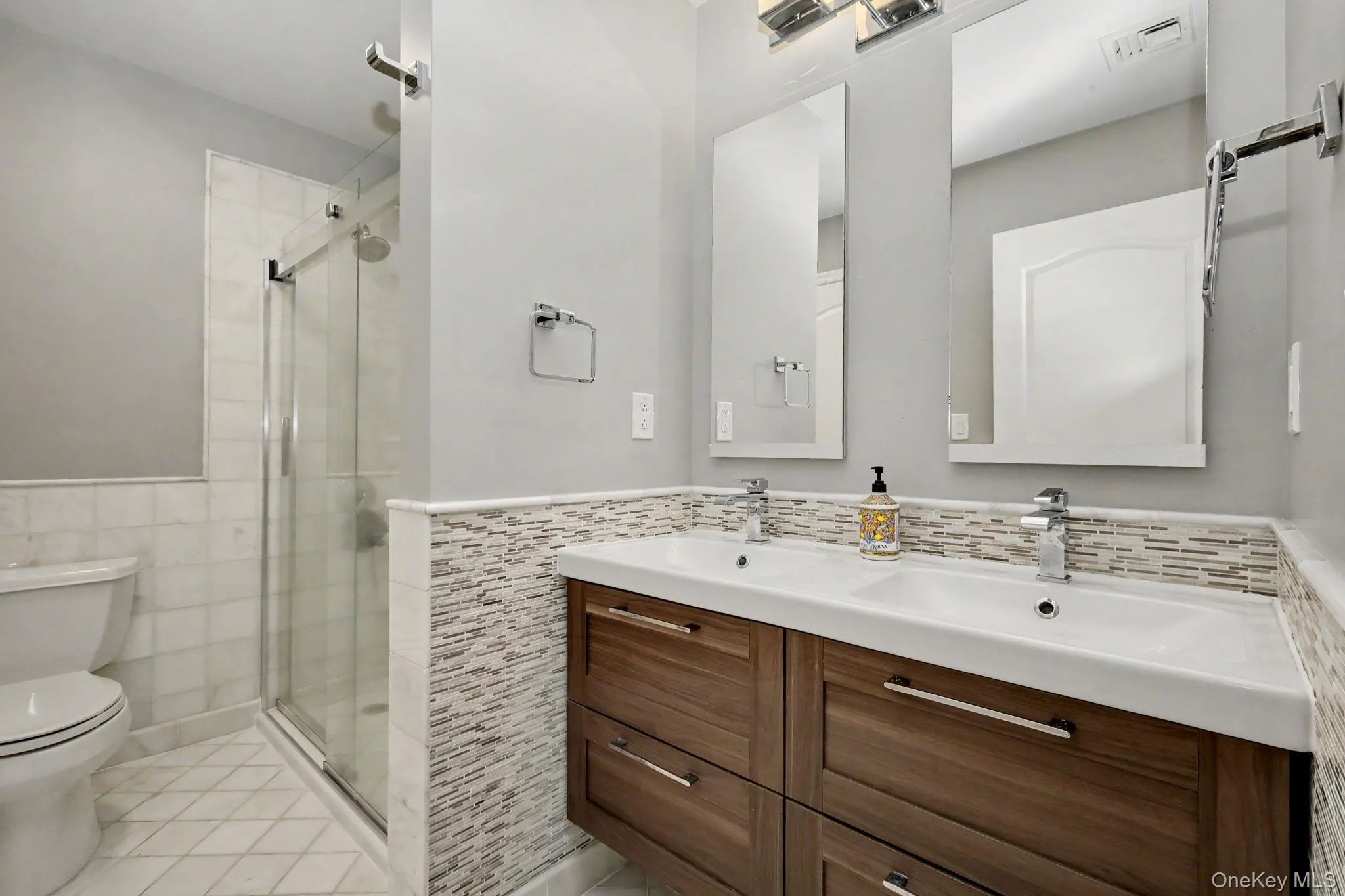 Dual sink vanity with mosaic tile and double glass door shower Dual sink vanity with mosaic tile and double glass door shower
