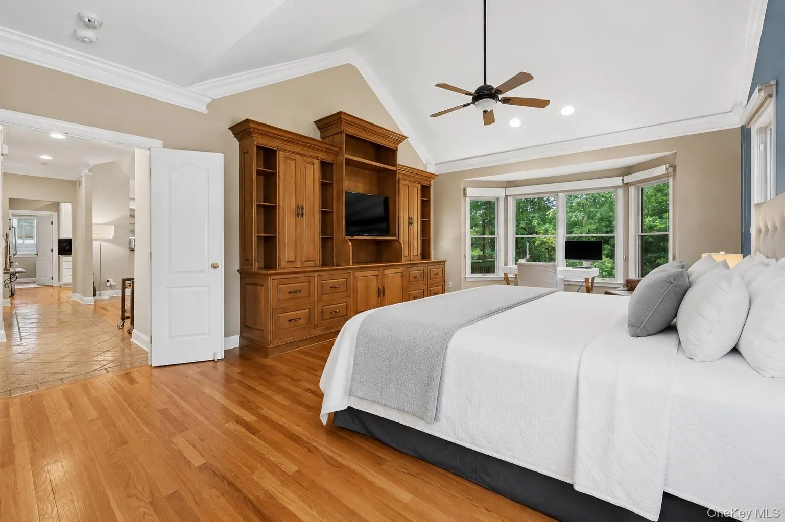 Vaulted ceiling with crown molding and ceiling fan, hardwood flooring, built-in storage unit, and a bay window Vaulted ceiling with crown molding and ceiling fan, hardwood flooring, built-in storage unit, and a bay window