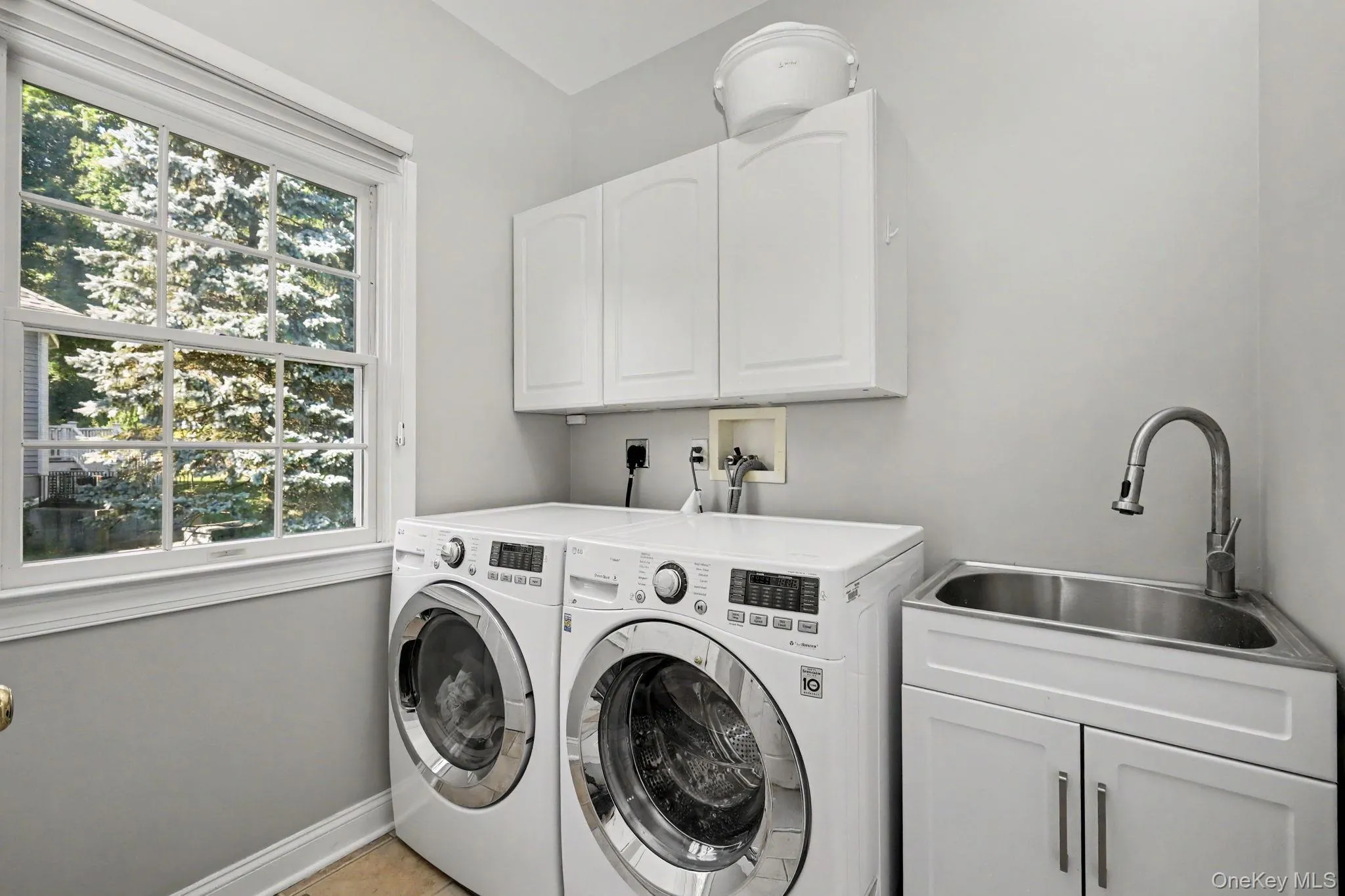 Dedicated laundry area, white cabinetry, and utility sink. Dedicated laundry area, white cabinetry, and utility sink.