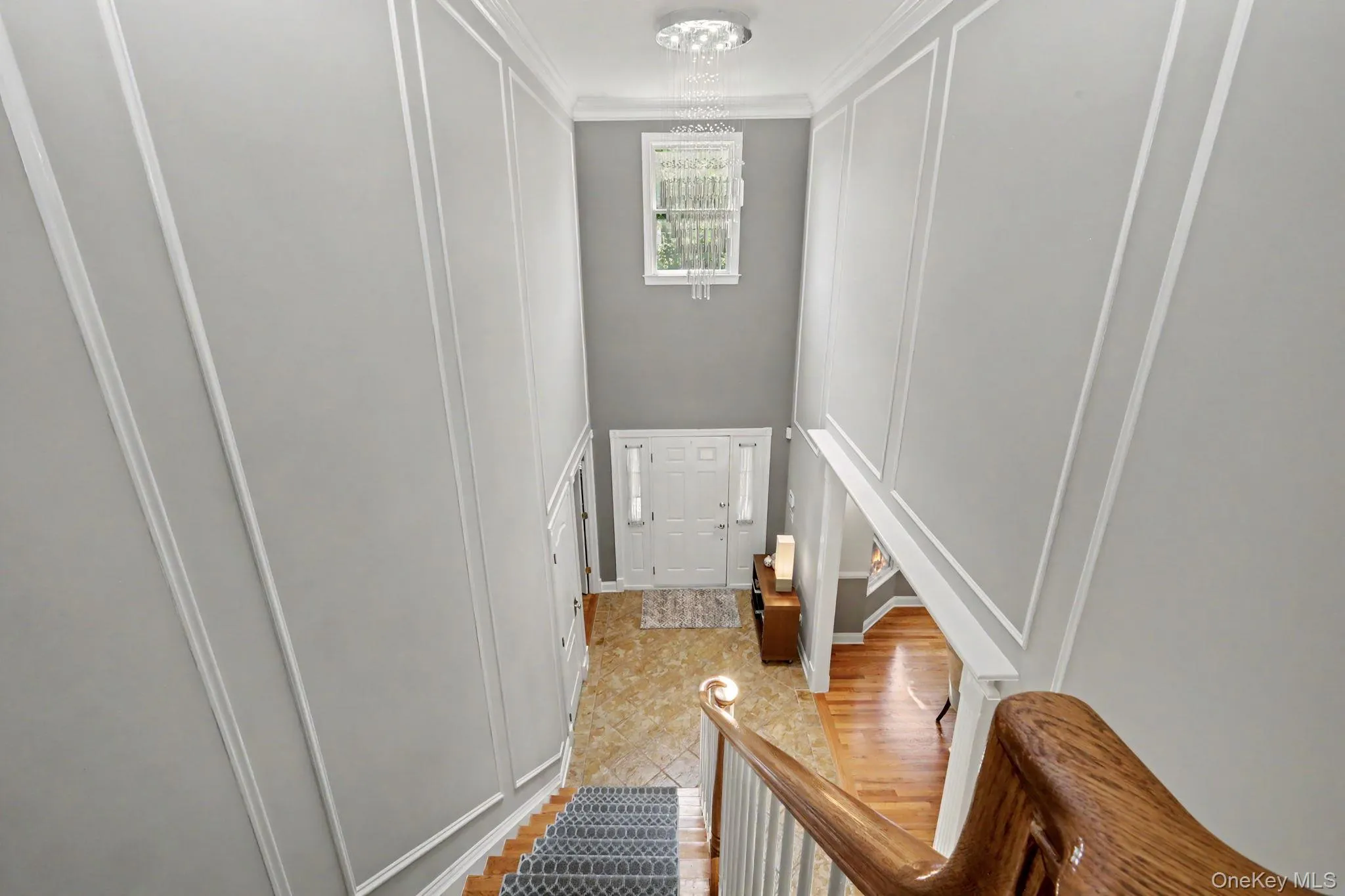 Two-story foyer featuring decorative wall paneling and a suspended chandelier Two-story foyer featuring decorative wall paneling and a suspended chandelier
