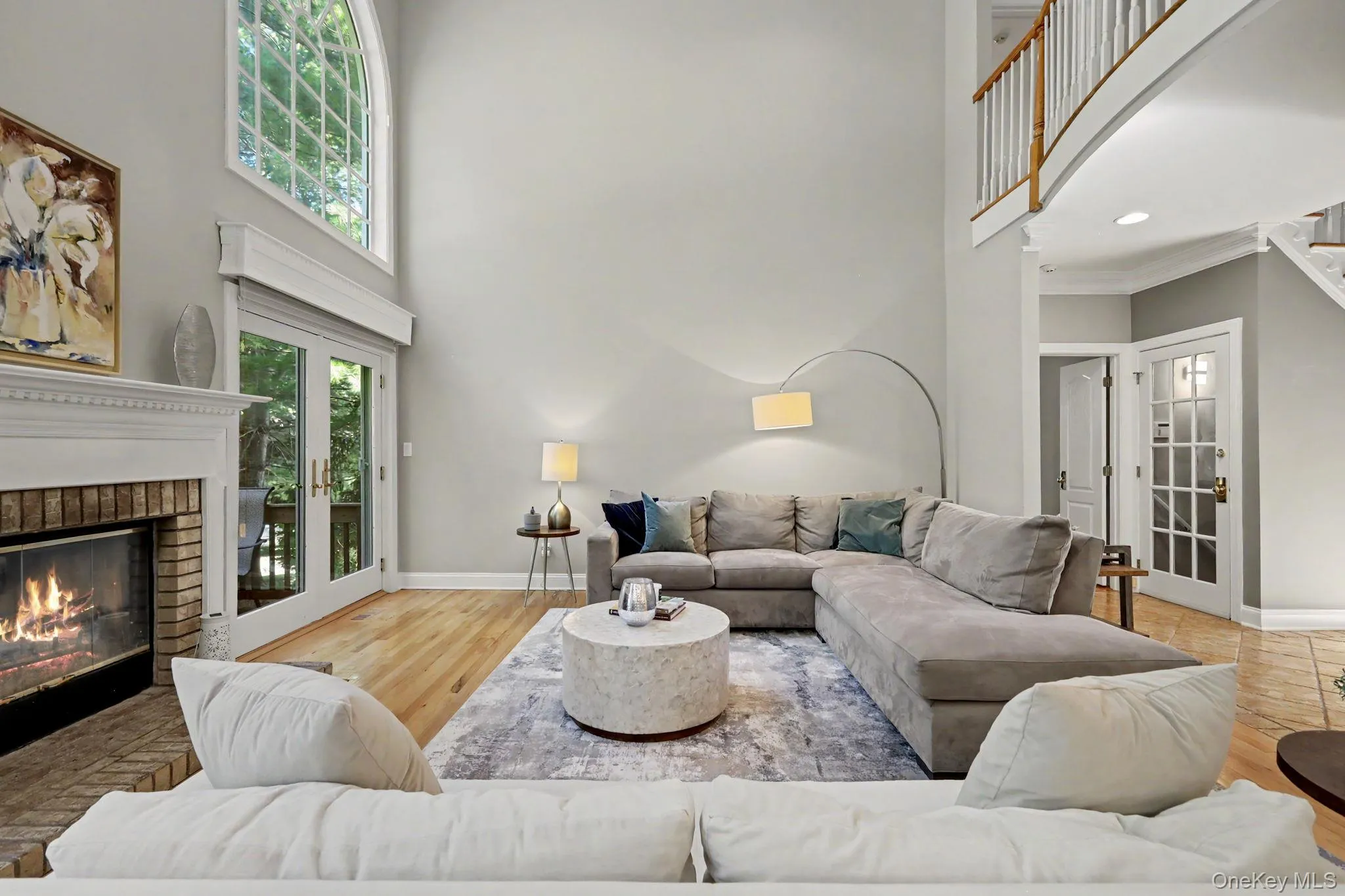 Two-story living area featuring fireplace, hardwood flooring, and an arched transom window. Two-story living area featuring fireplace, hardwood flooring, and an arched transom window.