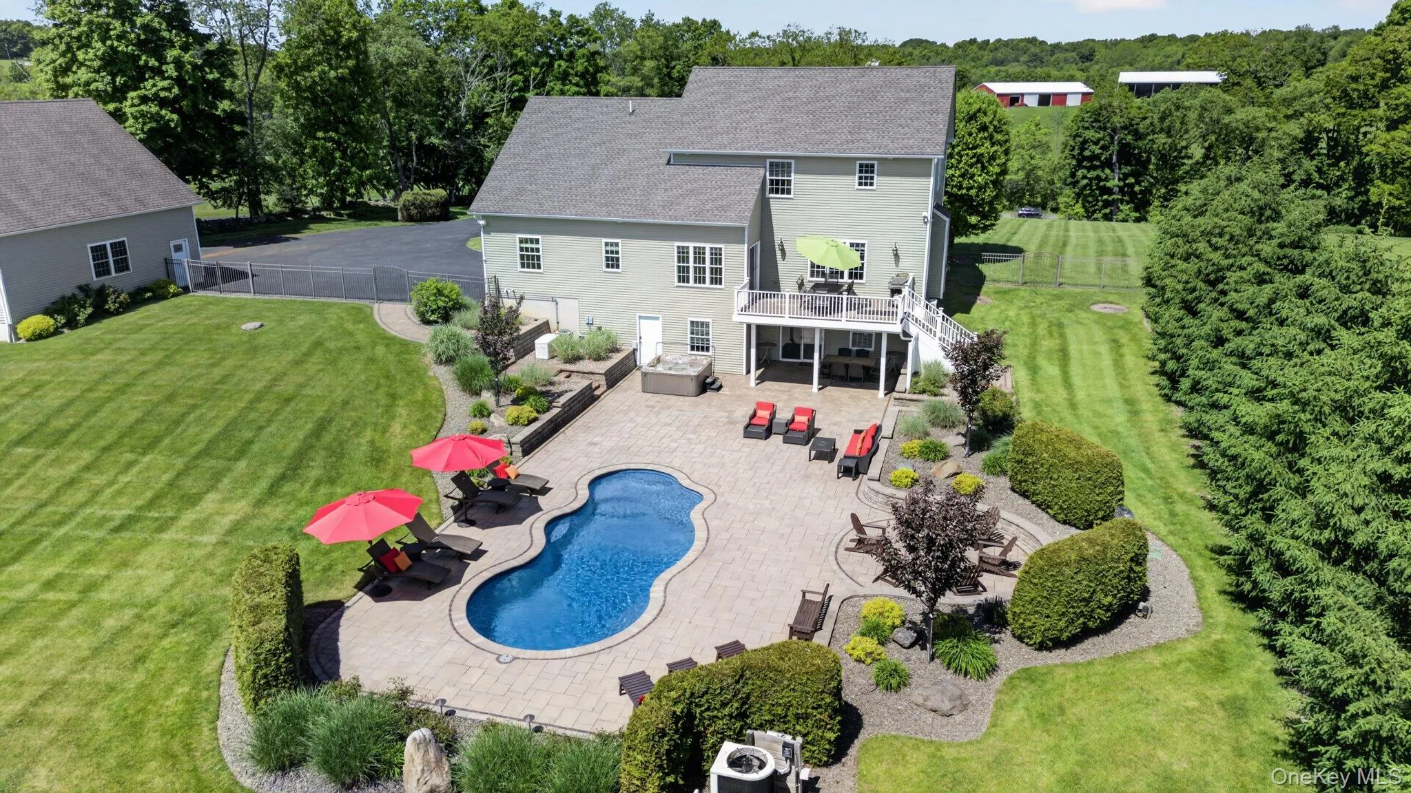 Backyard oasis featuring a kidney-shaped swimming pool, extensive paver patio, and multi-level landscaping Backyard oasis featuring a kidney-shaped swimming pool, extensive paver patio, and multi-level landscaping
