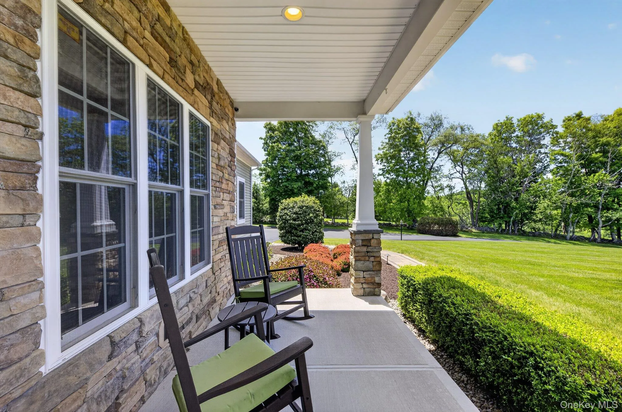 Stone veneer facade featuring a covered porch with white columns and a stone base Stone veneer facade featuring a covered porch with white columns and a stone base