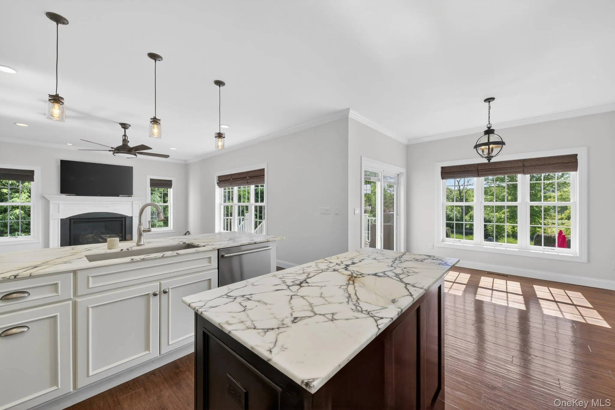 Kitchen island with white and dark veining countertop, wood-finish flooring, and pendant lighting Kitchen island with white and dark veining countertop, wood-finish flooring, and pendant lighting
