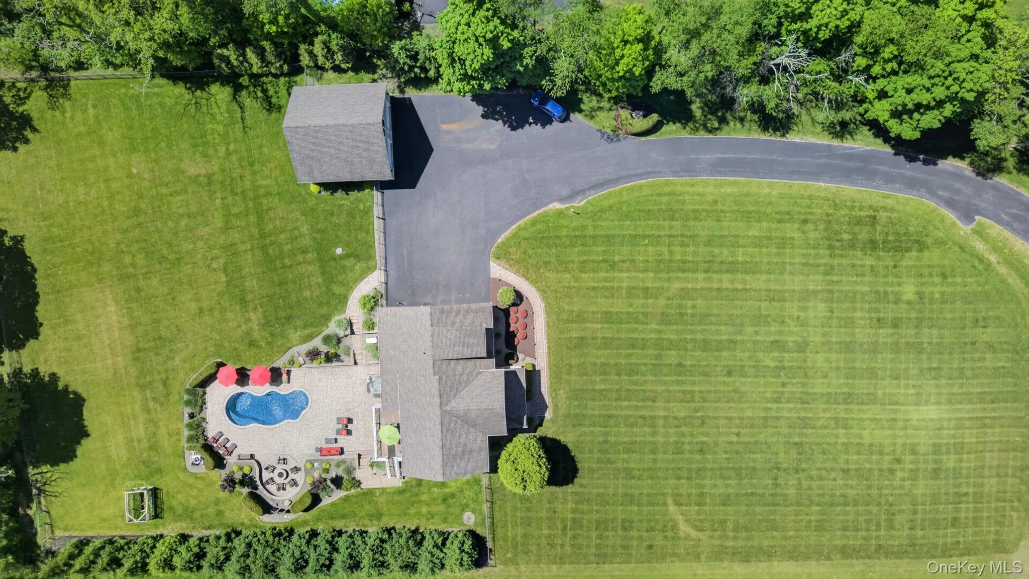 Expansive property featuring a winding asphalt driveway, detached garage, and a large inground freeform swimming pool Expansive property featuring a winding asphalt driveway, detached garage, and a large inground freeform swimming pool
