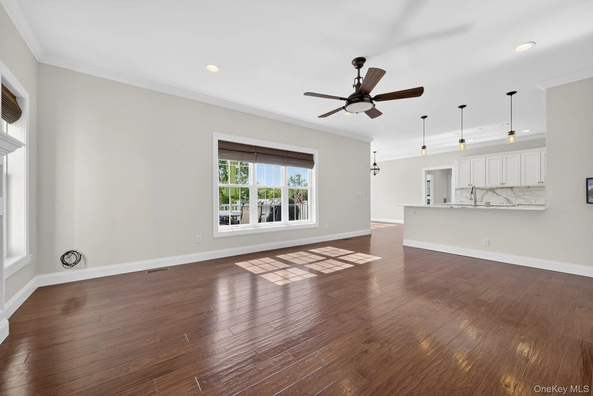 Open-concept living space featuring wood-finish flooring, a contemporary ceiling fan, recessed lighting, and crown molding Open-concept living space featuring wood-finish flooring, a contemporary ceiling fan, recessed lighting, and crown molding