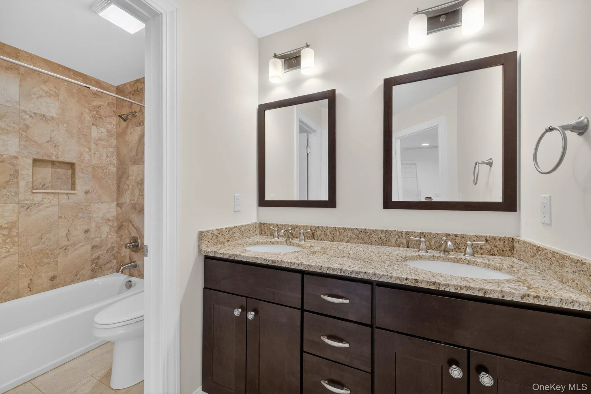 Dual vanity featuring granite countertops, undermount sinks, and dark wood-finish cabinetry with brushed nickel hardware Dual vanity featuring granite countertops, undermount sinks, and dark wood-finish cabinetry with brushed nickel hardware