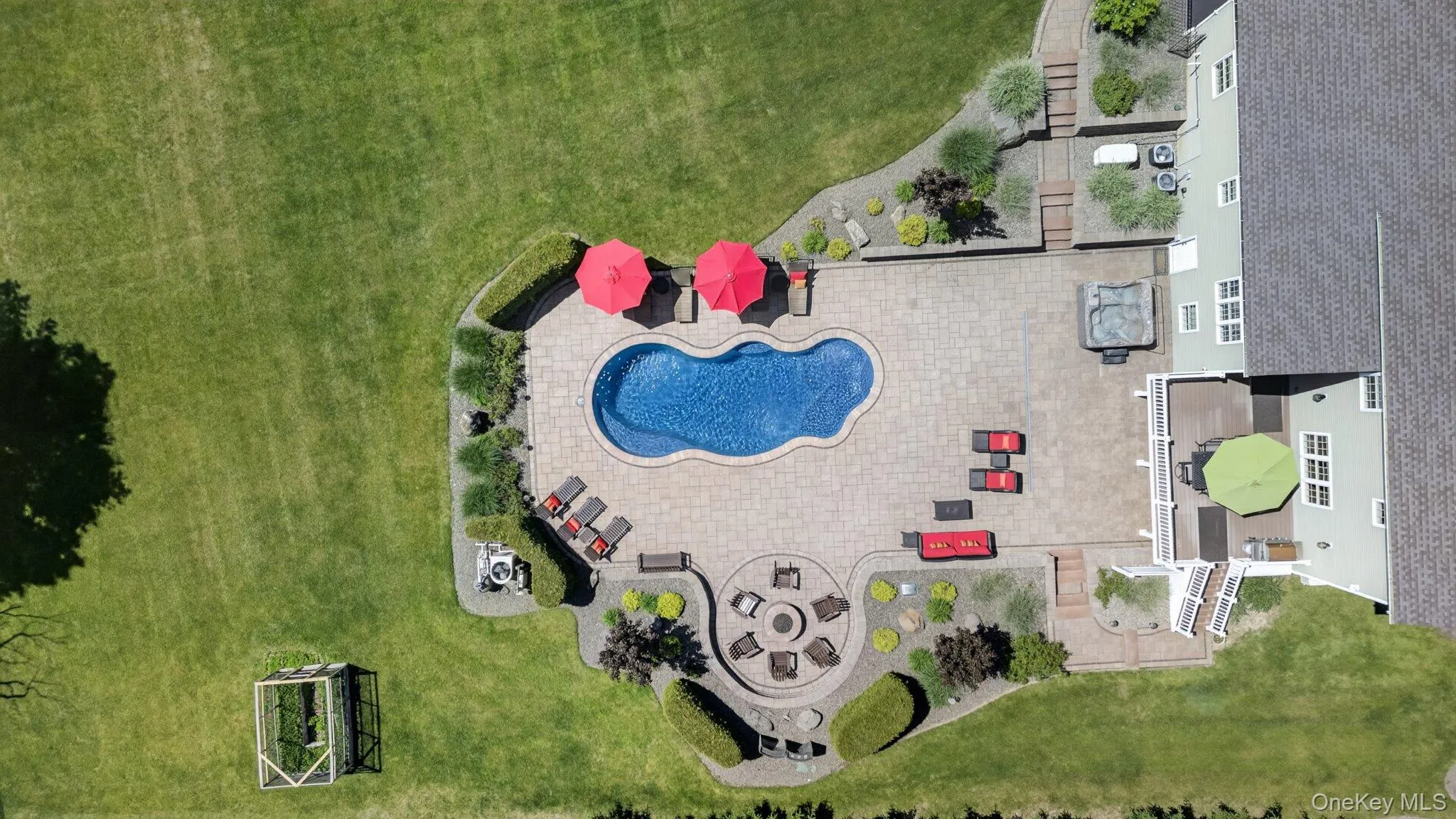 Expansive backyard featuring a freeform swimming pool with integrated spa, paver patio, and built-in fire pit area Expansive backyard featuring a freeform swimming pool with integrated spa, paver patio, and built-in fire pit area