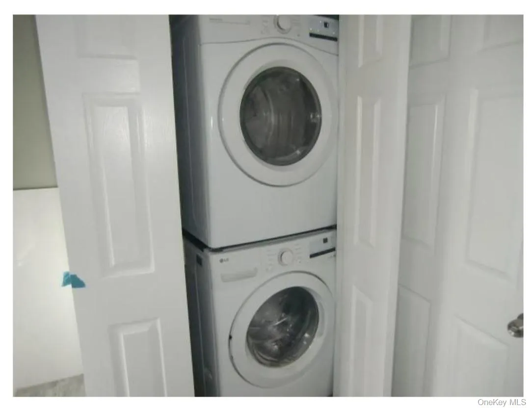 Clothes washing area with stacked washer and dryer and laundry area Clothes washing area with stacked washer and dryer and laundry area