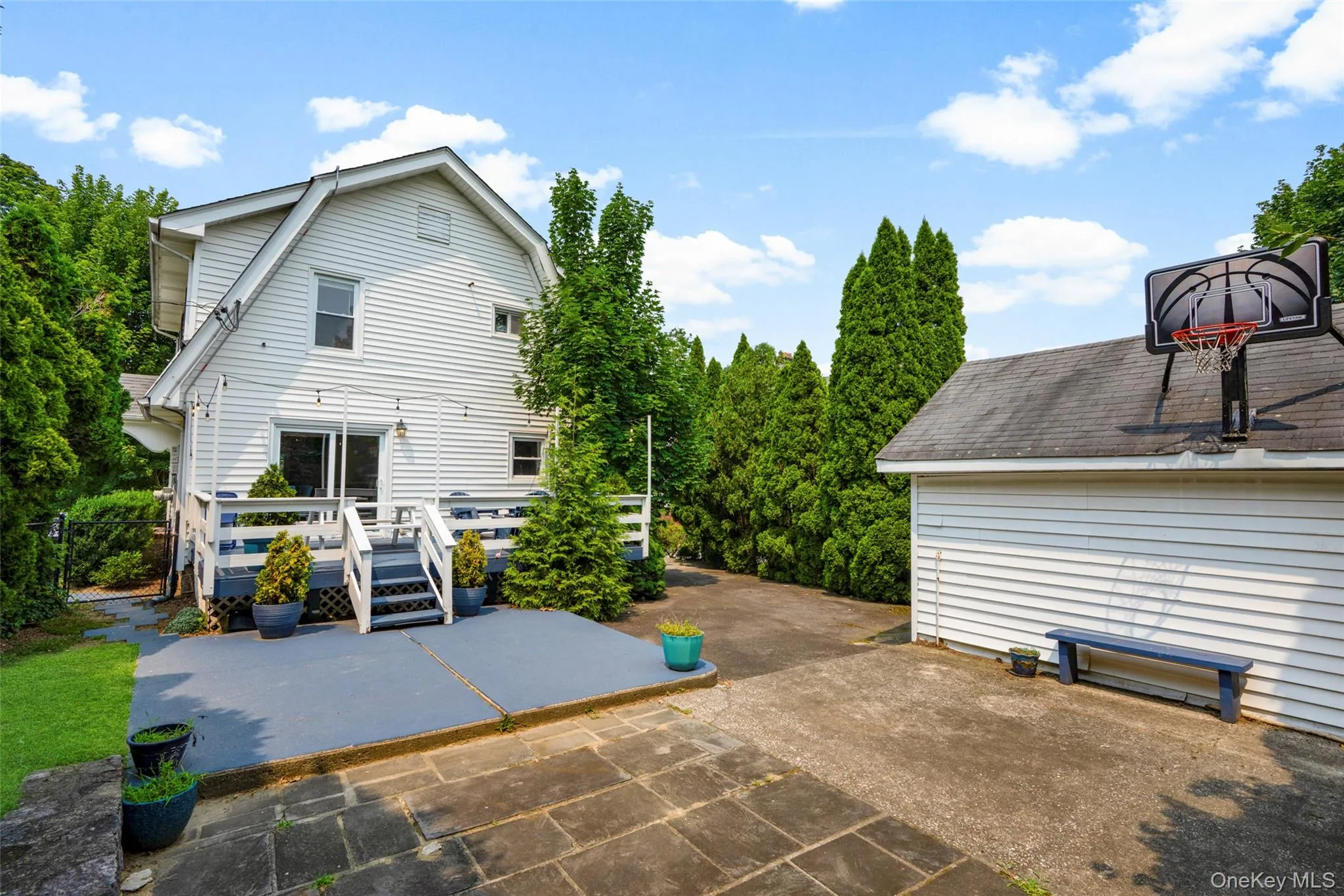 Rear exterior featuring a multi-level deck with white railings, a concrete patio, and even a basketball hoop! Rear exterior featuring a multi-level deck with white railings, a concrete patio, and even a basketball hoop!