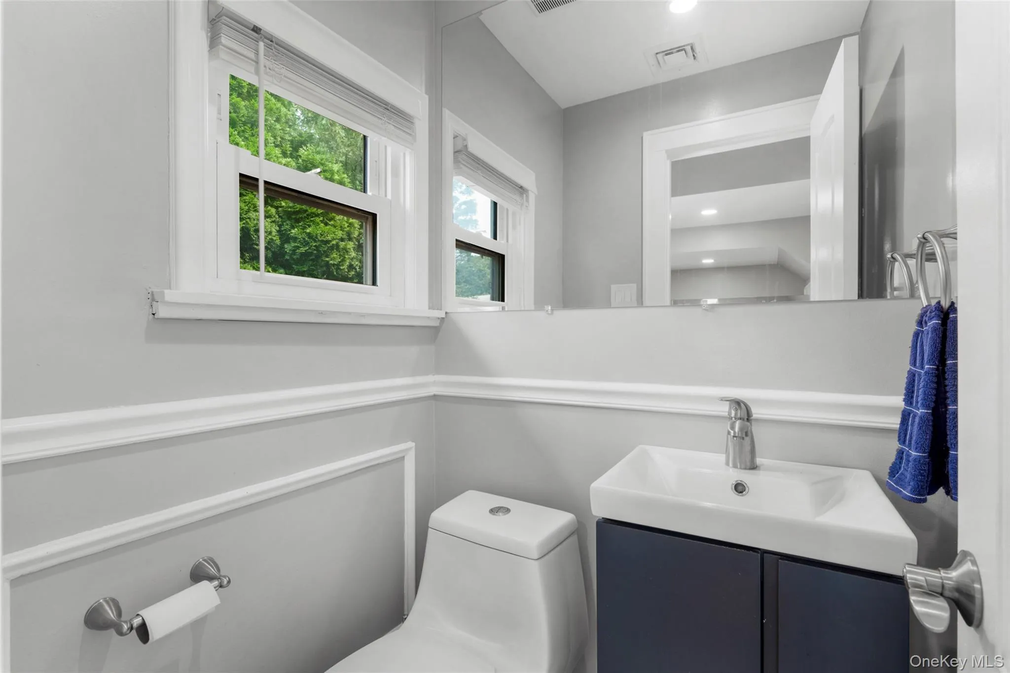 Contemporary bathroom featuring a wall-mounted vanity with integrated sink, chrome faucet, and full-width mirror Contemporary bathroom featuring a wall-mounted vanity with integrated sink, chrome faucet, and full-width mirror
