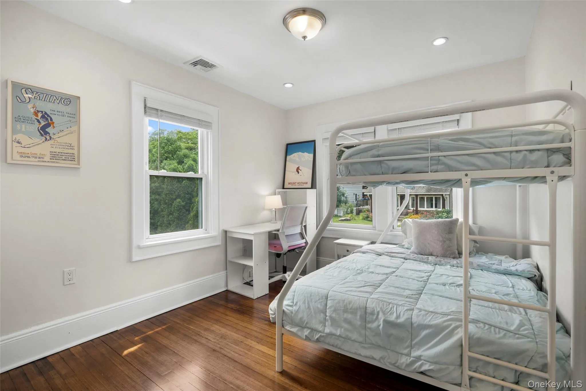 Bright bedroom featuring hardwood flooring, white trim, recessed lighting, and a double exposure. Bright bedroom featuring hardwood flooring, white trim, recessed lighting, and a double exposure.