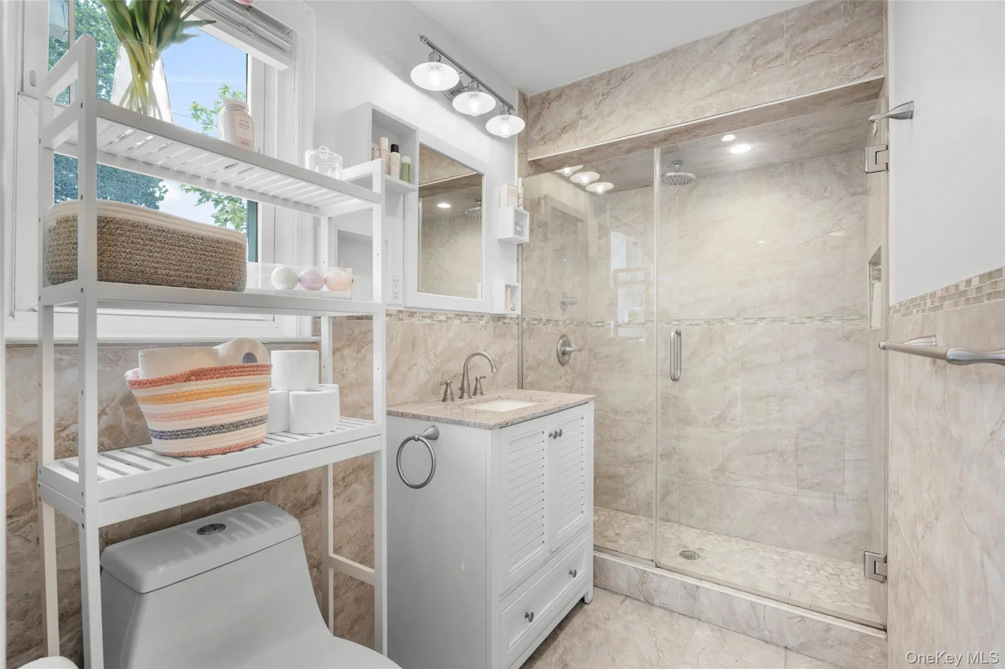 Full bathroom featuring a glass-enclosed shower with recessed lighting, a built-in shower niche, and a rain showerhead Full bathroom featuring a glass-enclosed shower with recessed lighting, a built-in shower niche, and a rain showerhead