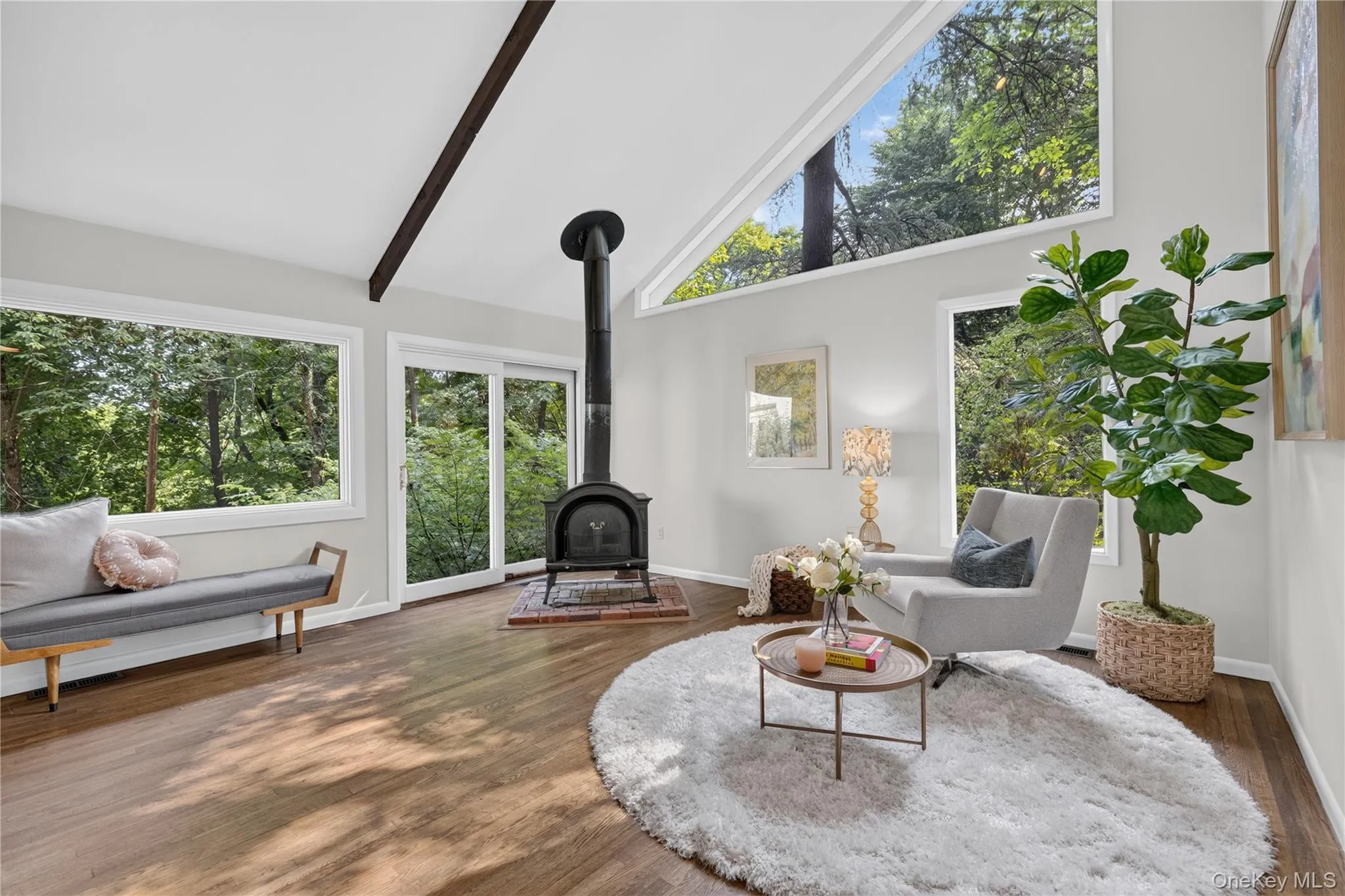 Sunny living room at 1,300 sq ft with walls of windows and wood-burning stove Sunny living room at 1,300 sq ft with walls of windows and wood-burning stove