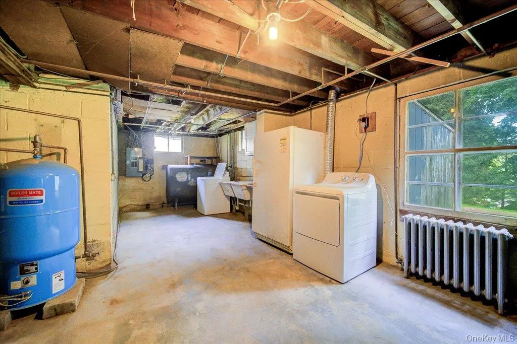 Basement utility area featuring exposed wood beam ceiling, concrete flooring, and a large multi-pane window Basement utility area featuring exposed wood beam ceiling, concrete flooring, and a large multi-pane window