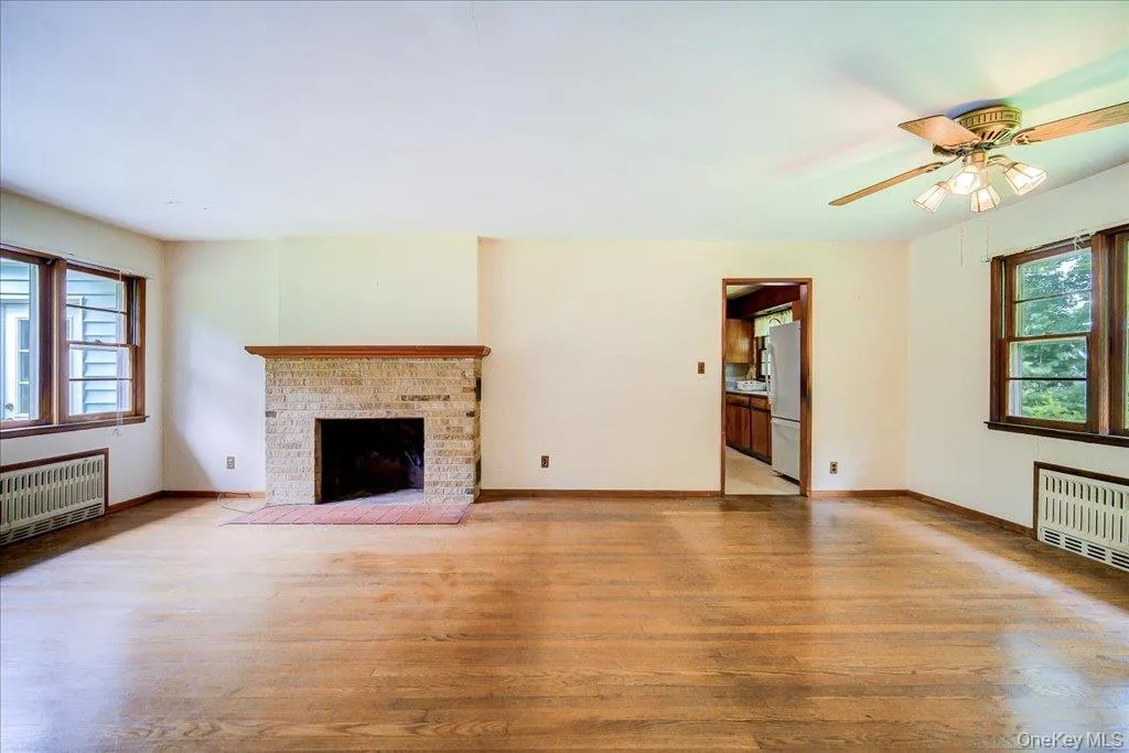 Living area featuring wood-finish flooring and a stone-faced fireplace with a wood mantel. living/dining area Living area featuring wood-finish flooring and a stone-faced fireplace with a wood mantel. living/dining area