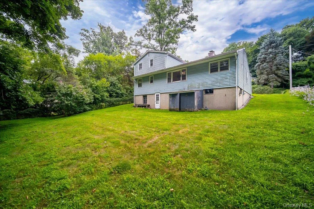 Expansive green lawn bordering a two-story residence with light blue siding and a concrete foundation Expansive green lawn bordering a two-story residence with light blue siding and a concrete foundation