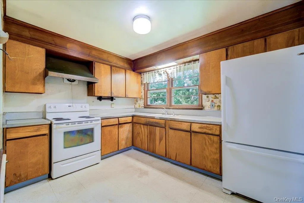Kitchen featuring wood-finish cabinetry, white countertops, and white appliances Kitchen featuring wood-finish cabinetry, white countertops, and white appliances