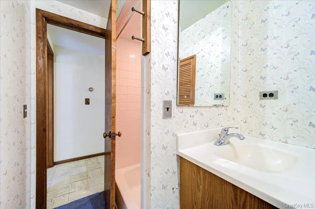 Bathroom featuring a single vanity with an integrated sink, chrome faucet, and a wall-mounted mirror Bathroom featuring a single vanity with an integrated sink, chrome faucet, and a wall-mounted mirror
