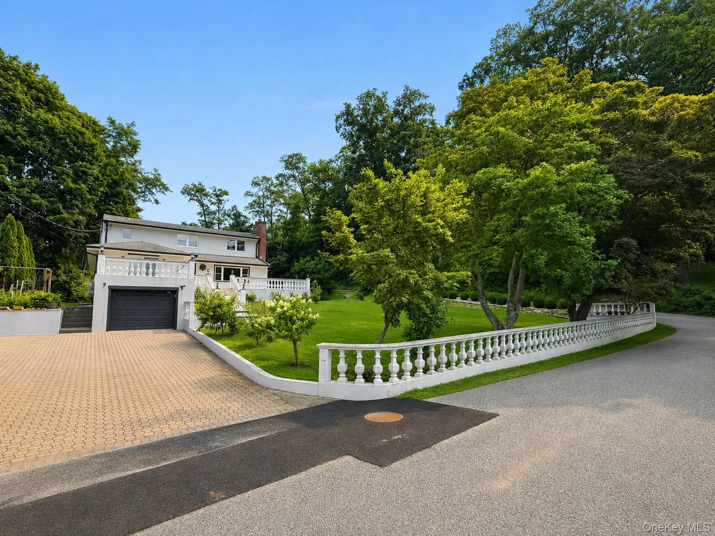 Front view showcasing the lush yard, elegant balustrade and expansive driveway while highlighting the inviting curb appeal Front view showcasing the lush yard, elegant balustrade and expansive driveway while highlighting the inviting curb appeal