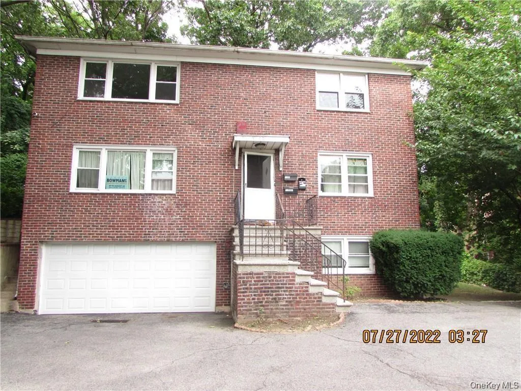 Two-story brick exterior featuring multiple windows and a prominent white garage door Two-story brick exterior featuring multiple windows and a prominent white garage door