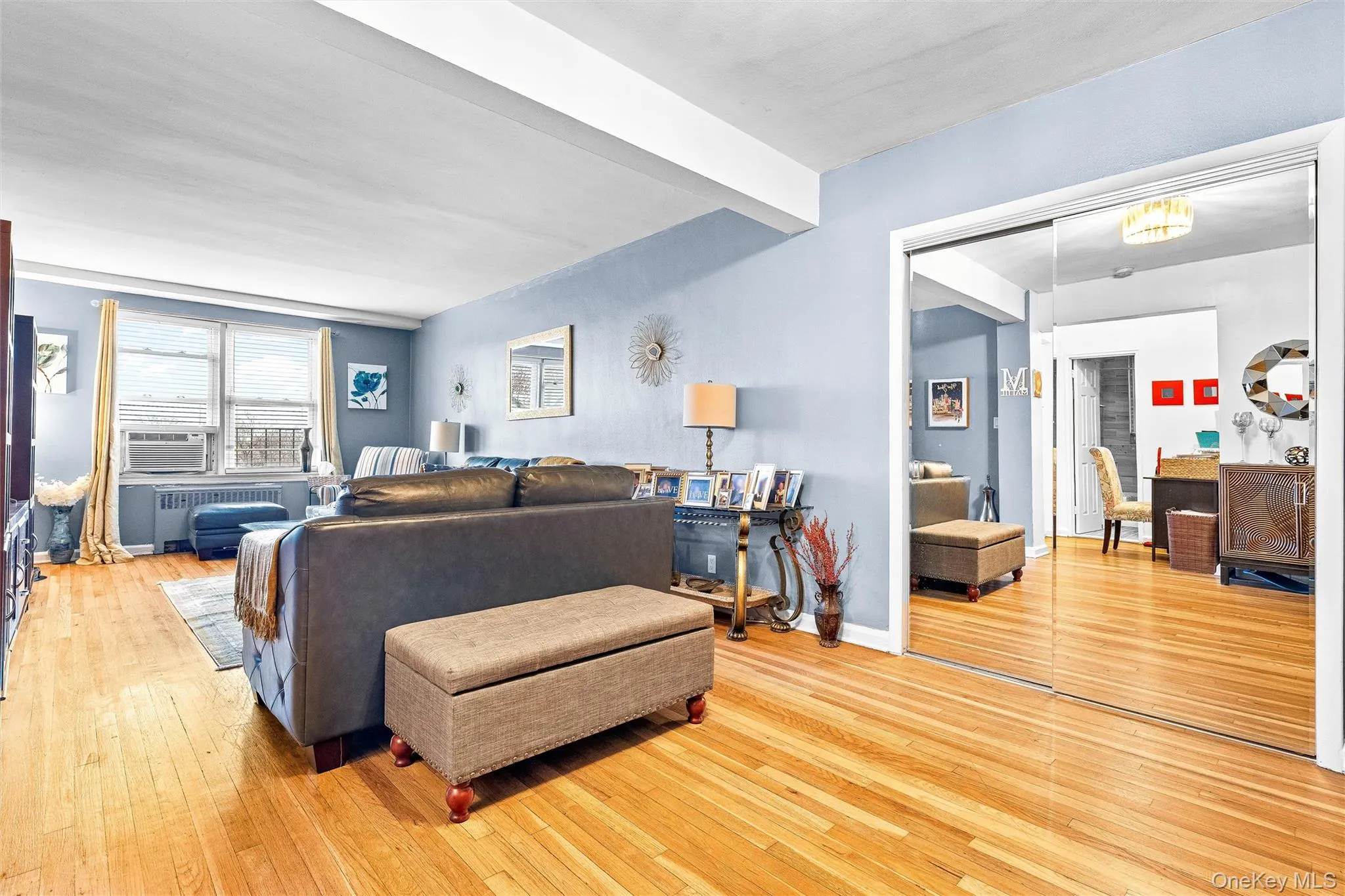 Living area featuring light wood-style floors, radiator, and cooling unit Living area featuring light wood-style floors, radiator, and cooling unit