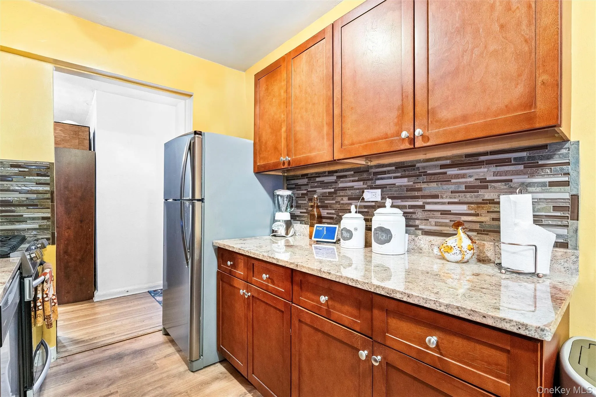 Kitchen with light wood-style flooring, range, light stone countertops, and tasteful backsplash Kitchen with light wood-style flooring, range, light stone countertops, and tasteful backsplash