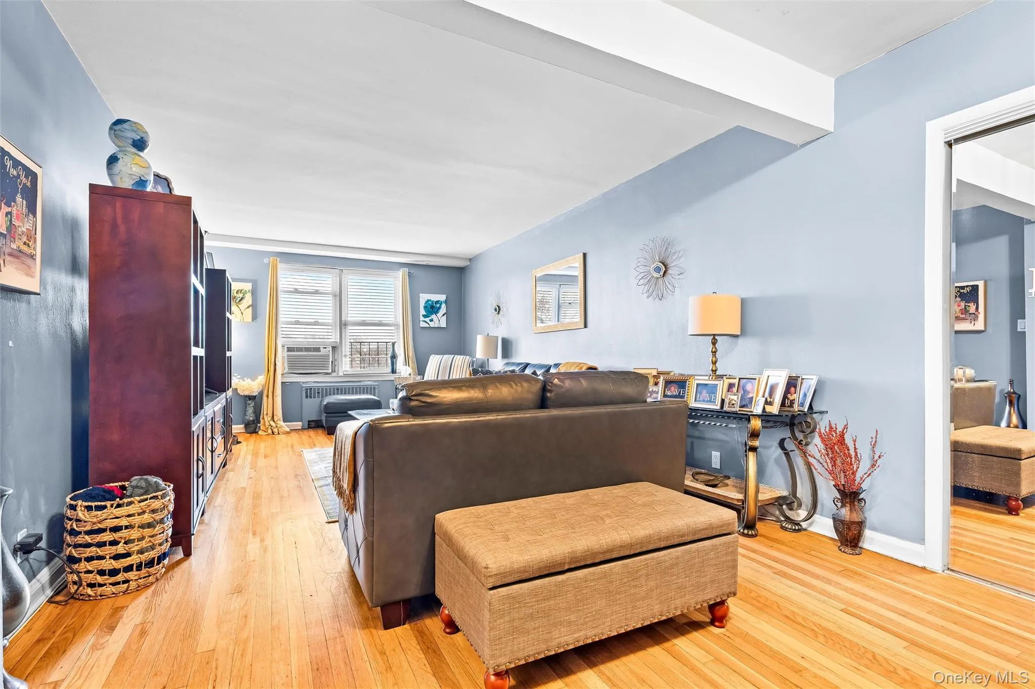 Living area with baseboards, light wood-style flooring, radiator, and cooling unit Living area with baseboards, light wood-style flooring, radiator, and cooling unit