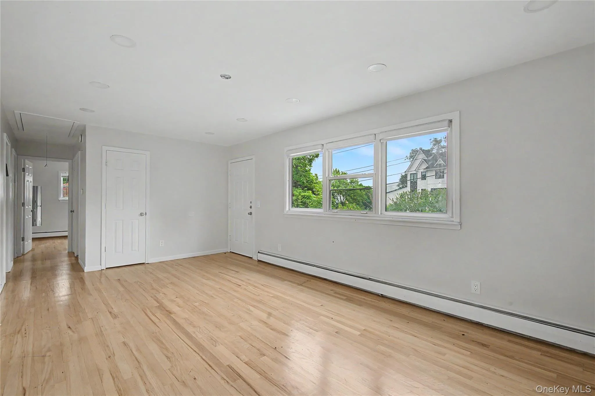 Open and airy living room with large windows and warm hardwood flooring. Open and airy living room with large windows and warm hardwood flooring.