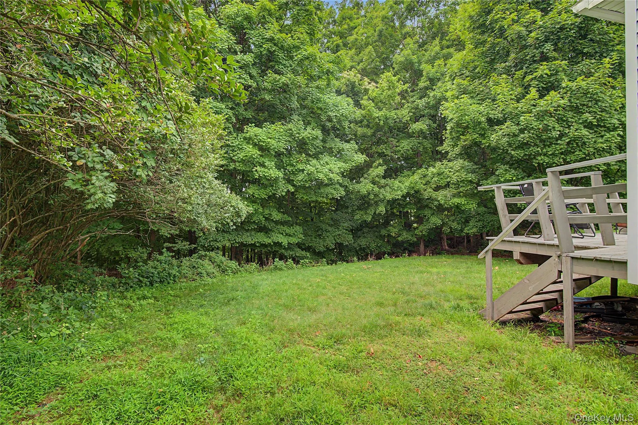 Serene backyard retreat with a deck and wooded privacy. Serene backyard retreat with a deck and wooded privacy.