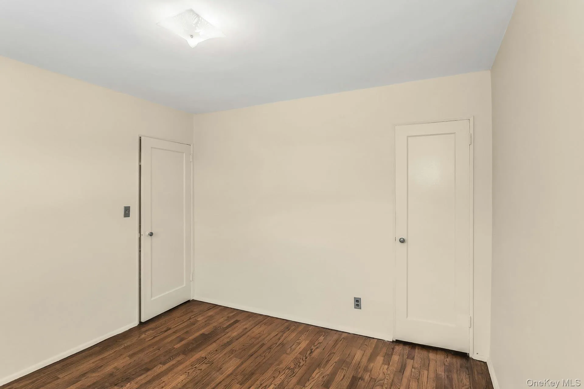 Spare room featuring dark wood-type flooring and baseboards Spare room featuring dark wood-type flooring and baseboards