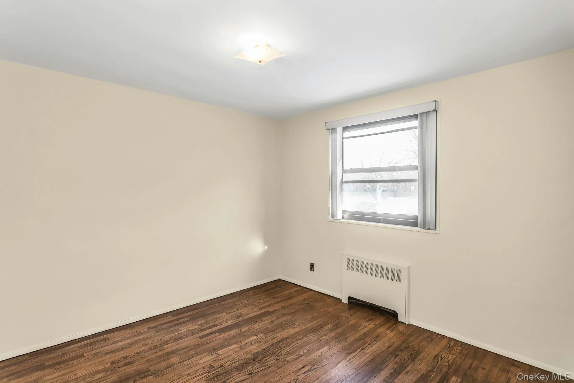 Empty room featuring radiator and dark wood-type flooring Empty room featuring radiator and dark wood-type flooring