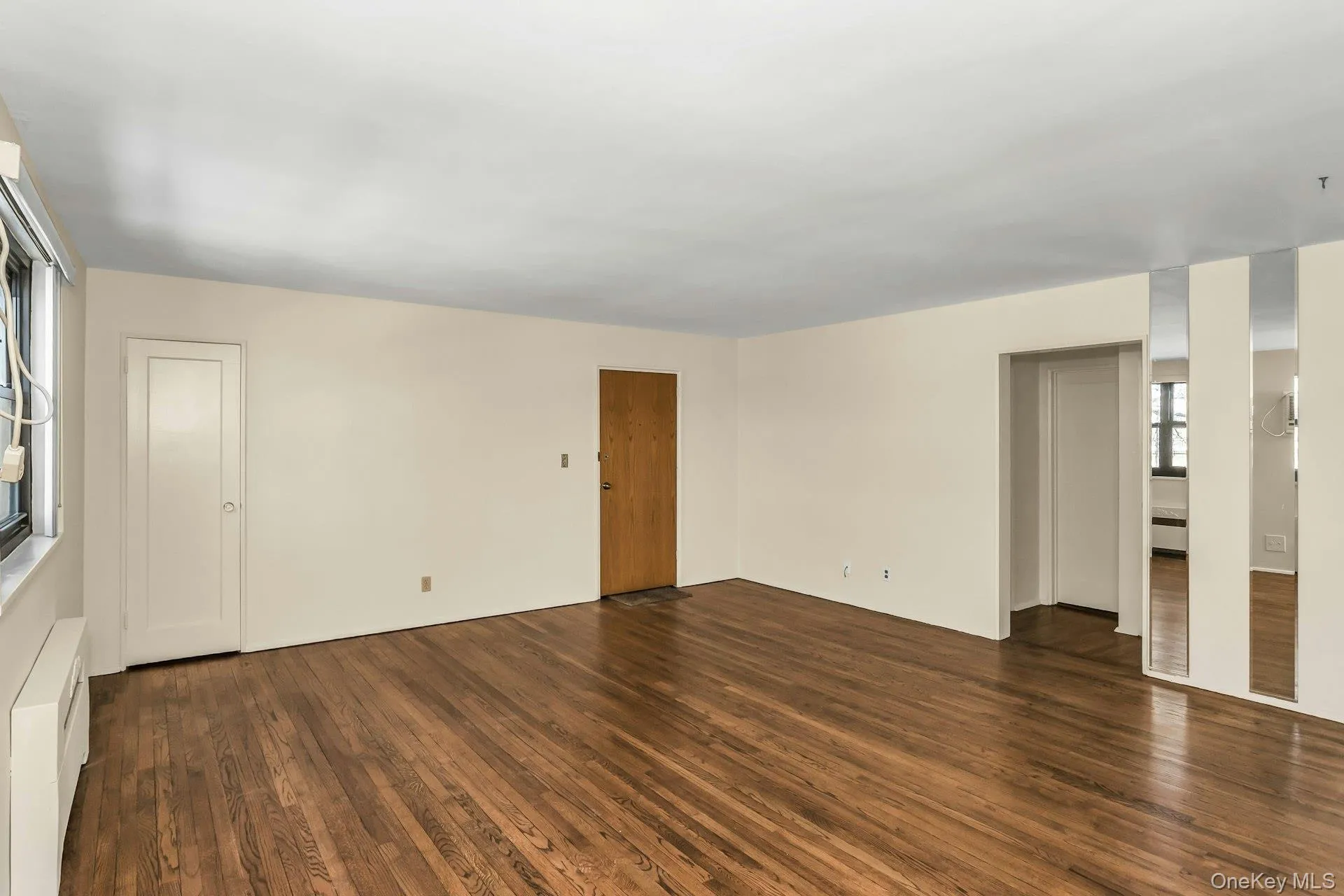 Unfurnished room with radiator and dark wood finished floors Unfurnished room with radiator and dark wood finished floors